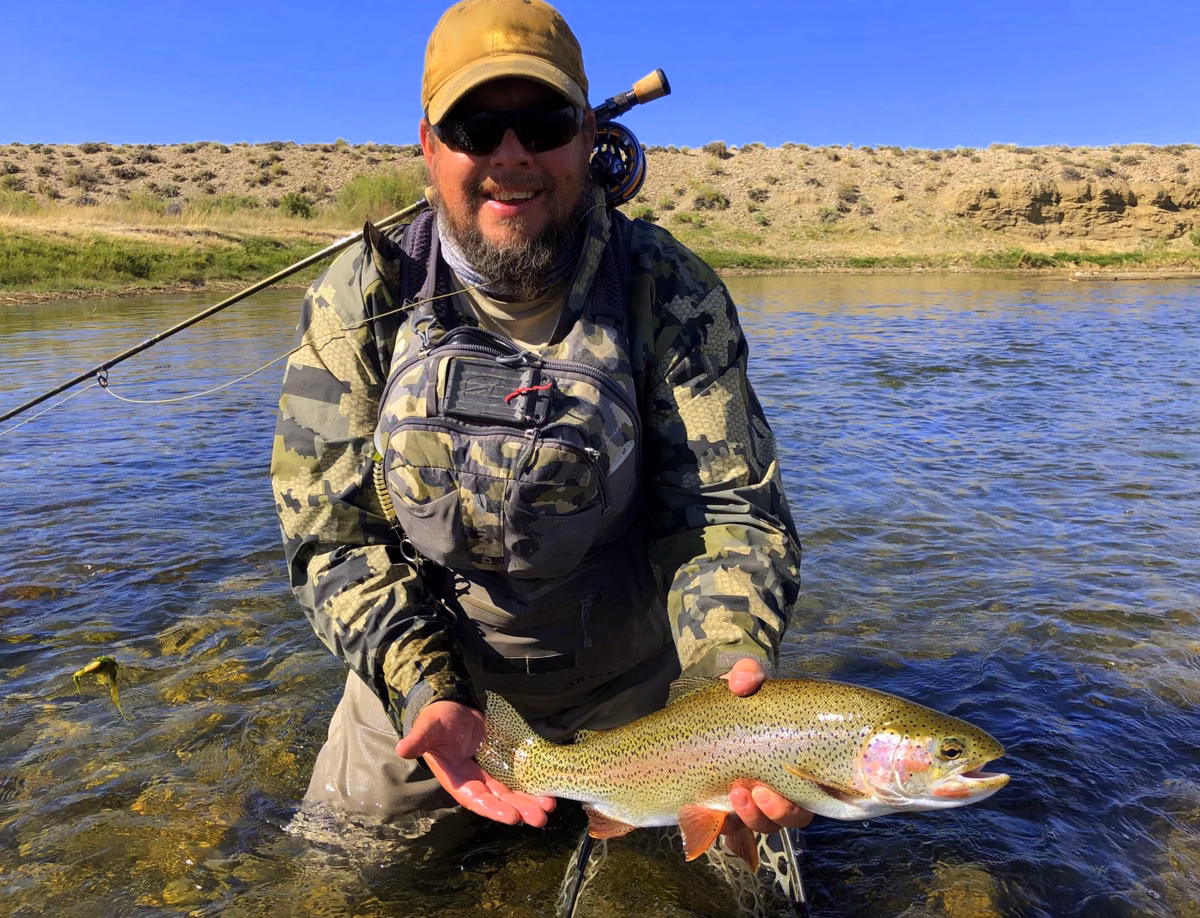 Fly angler holding a rainbow trout in a river (photographed out of state)